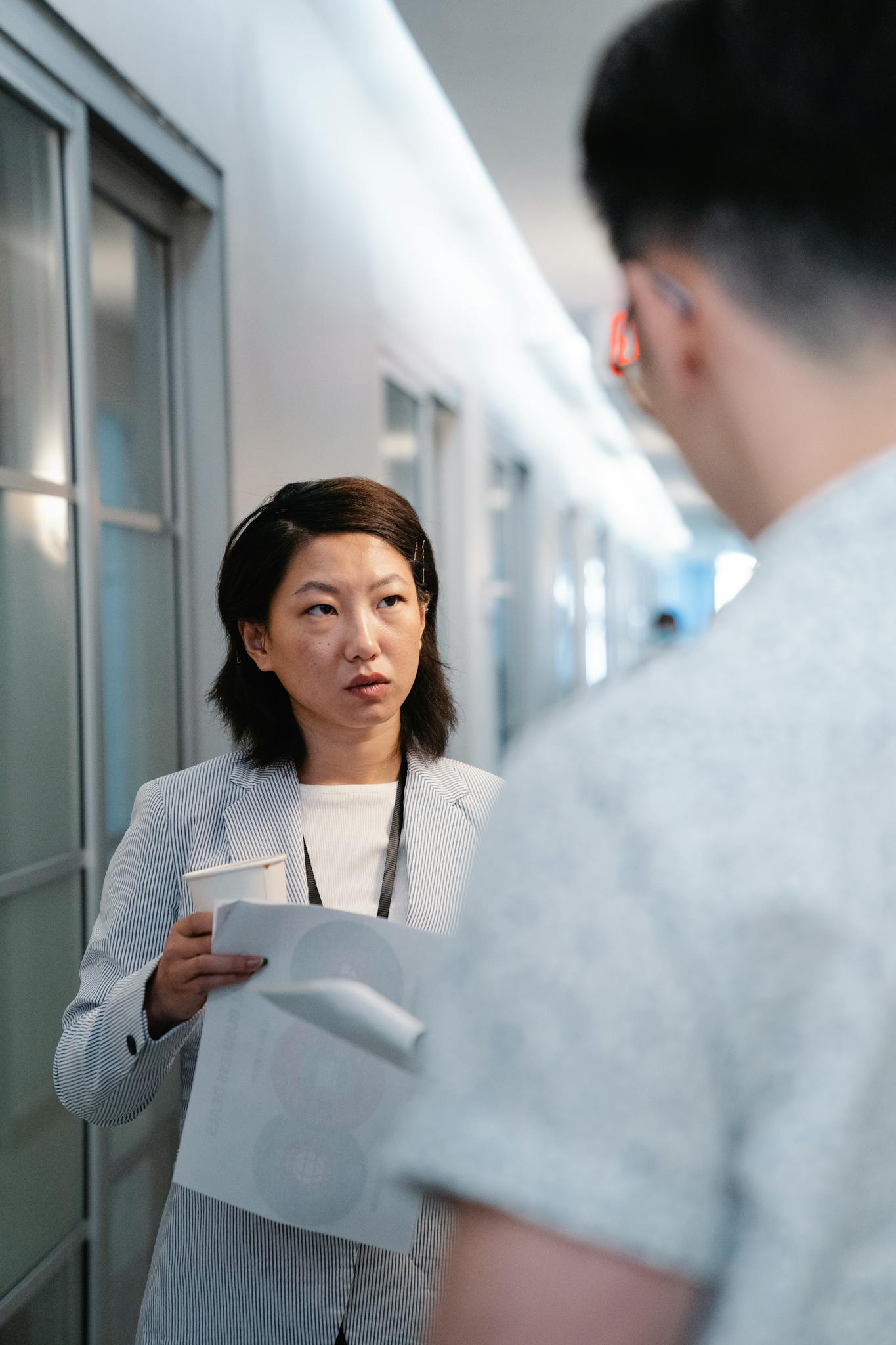 Two colleagues discussing work in an office hallway.